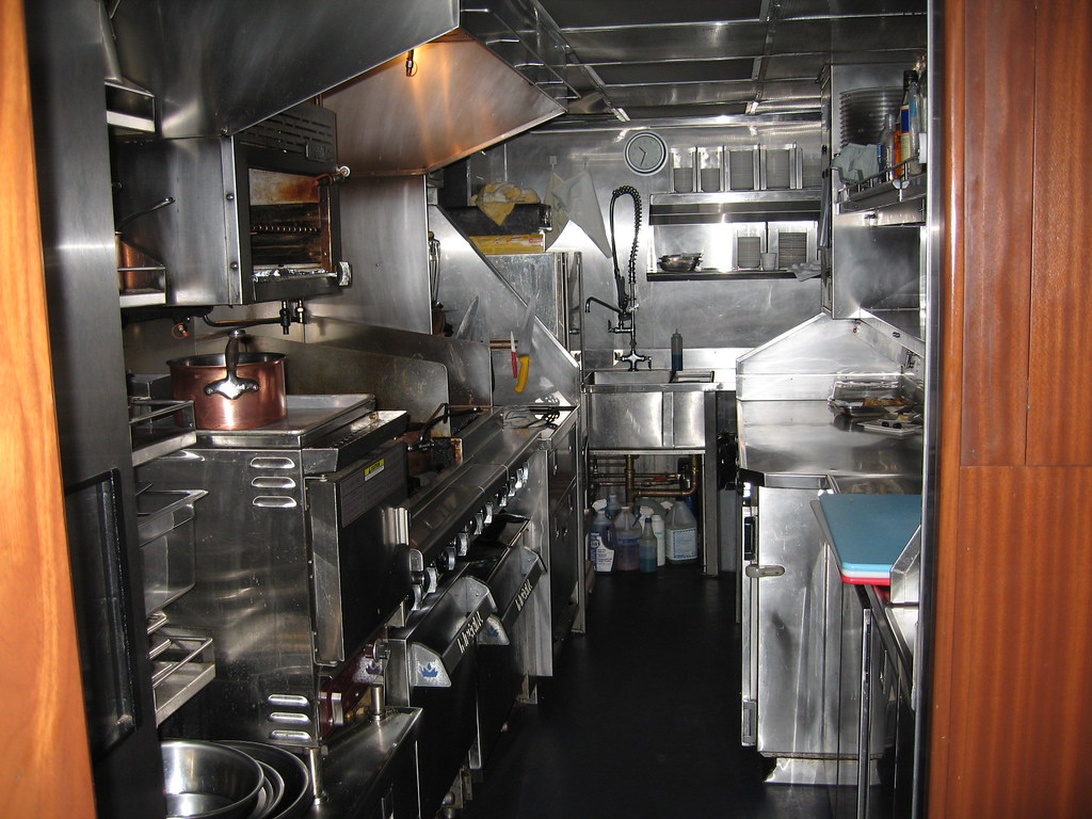 En tekniker som utför service på en kommersiell kyl i ett restaurangkök.
